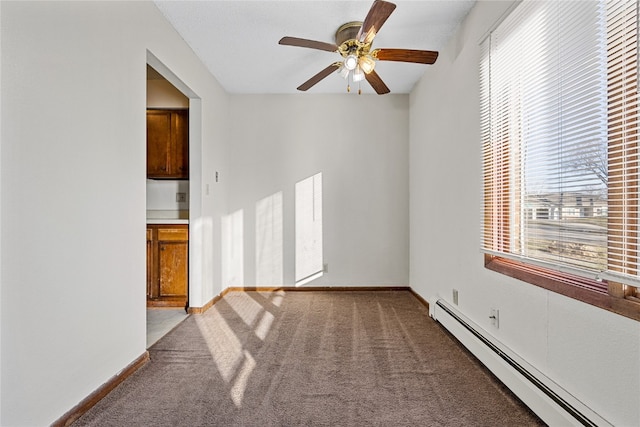 carpeted empty room featuring ceiling fan and a baseboard heating unit