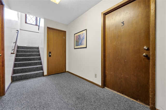 carpeted entryway with a textured ceiling