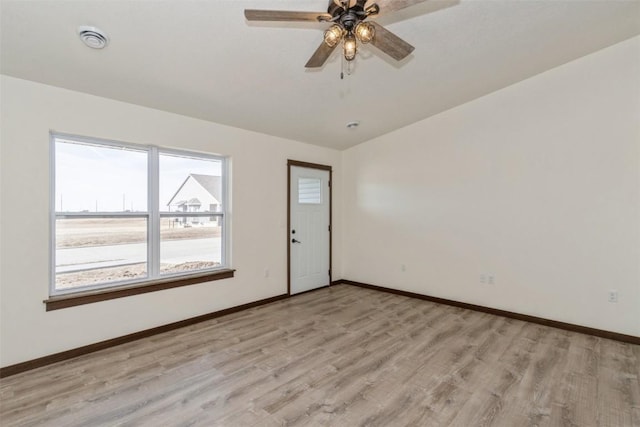 spare room featuring baseboards, lofted ceiling, and light wood finished floors