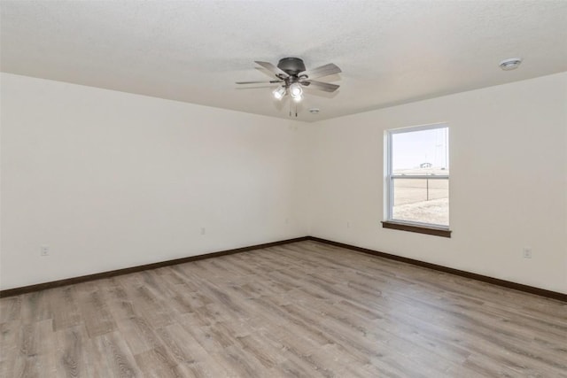 unfurnished room with ceiling fan, light wood-style flooring, baseboards, and a textured ceiling