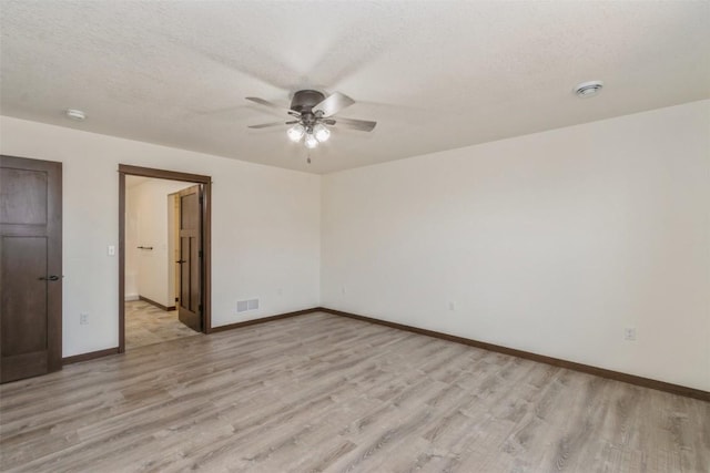 empty room featuring light wood-type flooring, visible vents, and baseboards