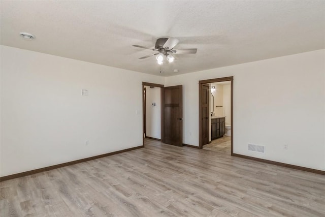 empty room with a ceiling fan, visible vents, baseboards, light wood-style flooring, and a textured ceiling