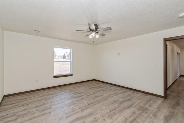 spare room featuring baseboards, a textured ceiling, a ceiling fan, and light wood finished floors