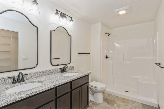 bathroom with double vanity, toilet, a shower, and a sink