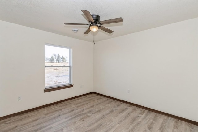 empty room featuring light wood finished floors, ceiling fan, a textured ceiling, and baseboards