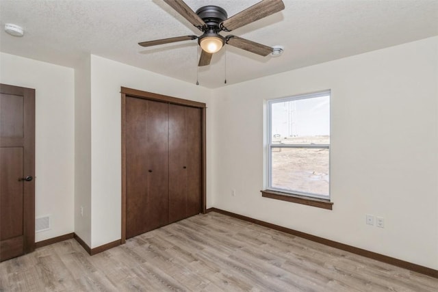 unfurnished bedroom featuring visible vents, light wood-style flooring, baseboards, and a closet