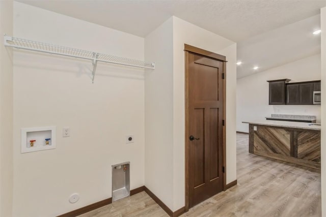 clothes washing area with baseboards, hookup for an electric dryer, light wood-style flooring, washer hookup, and hookup for a gas dryer