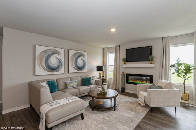 living area featuring a glass covered fireplace, baseboards, wood finished floors, and recessed lighting