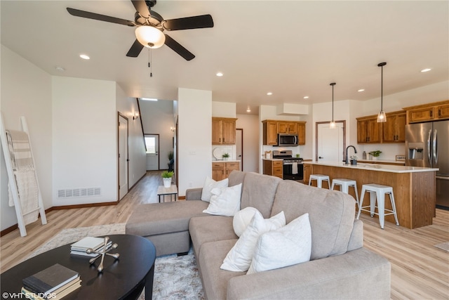 living room featuring light hardwood / wood-style floors, ceiling fan, and sink