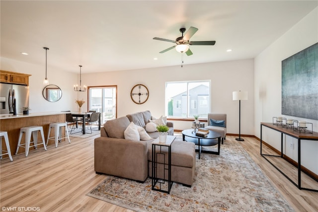 living room featuring light hardwood / wood-style floors and ceiling fan with notable chandelier