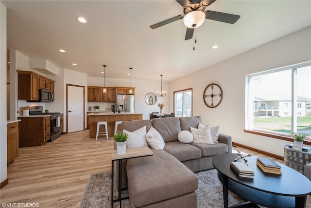 living room featuring plenty of natural light, light hardwood / wood-style floors, and ceiling fan with notable chandelier