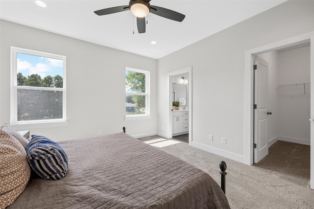 bedroom with ceiling fan, connected bathroom, light colored carpet, and multiple windows