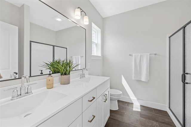 bathroom featuring a shower with shower door, toilet, and vanity