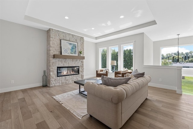 living room with light hardwood / wood-style floors, a raised ceiling, and a fireplace