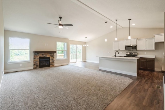 unfurnished living room featuring ceiling fan with notable chandelier, sink, vaulted ceiling with beams, dark hardwood / wood-style floors, and a fireplace