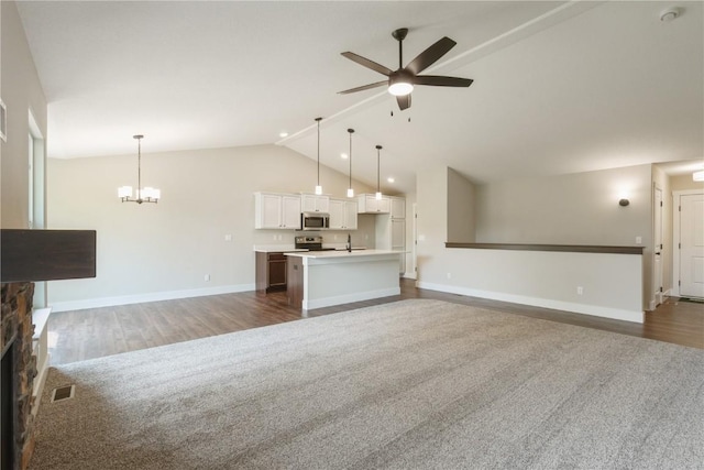 unfurnished living room featuring sink, high vaulted ceiling, dark hardwood / wood-style flooring, a fireplace, and ceiling fan with notable chandelier