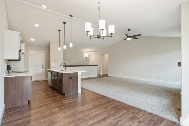 kitchen featuring white cabinetry, sink, hanging light fixtures, range, and a center island with sink