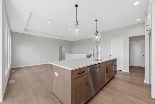 kitchen featuring visible vents, a raised ceiling, dishwasher, light wood-style flooring, and a sink