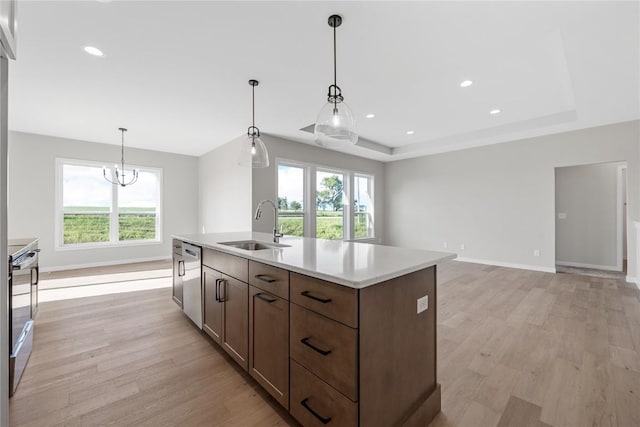 kitchen featuring a tray ceiling, light countertops, light wood-style floors, a sink, and range with electric cooktop