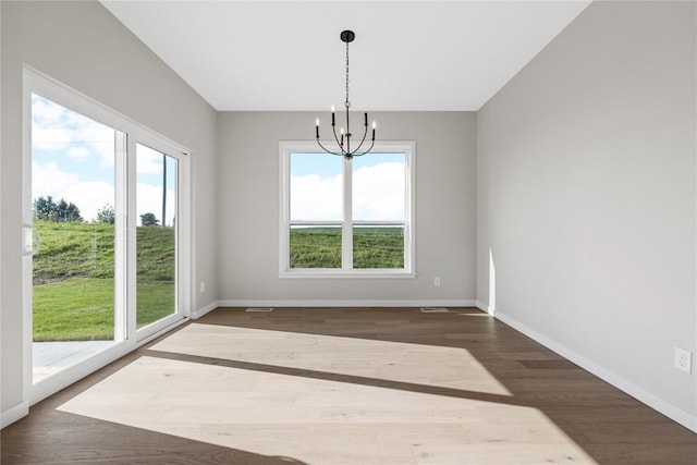 unfurnished dining area featuring baseboards, dark wood-type flooring, visible vents, and a notable chandelier