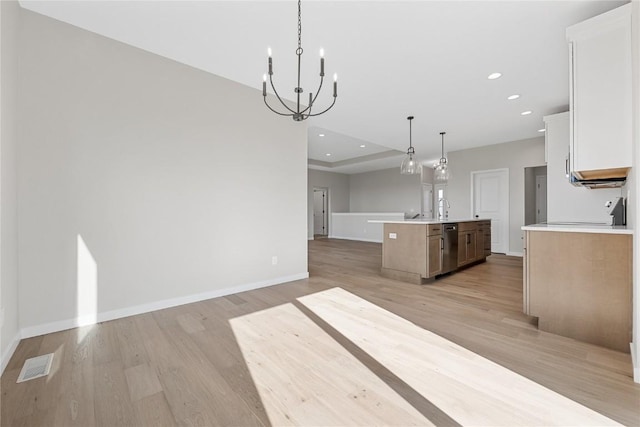 kitchen with light wood finished floors, light countertops, open floor plan, a sink, and dishwasher