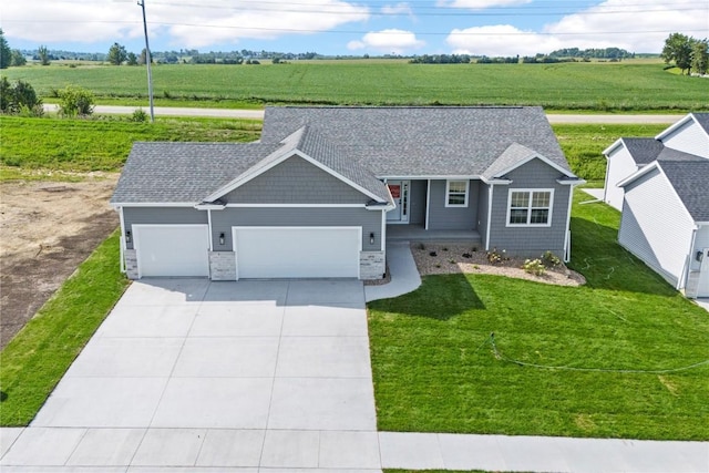 view of front of home featuring a garage, driveway, roof with shingles, and a rural view