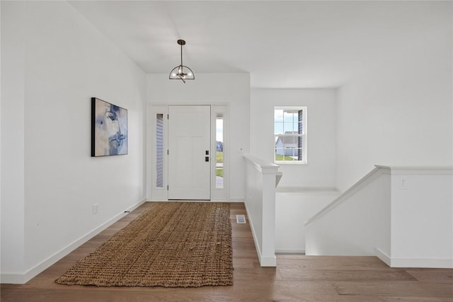 entryway with a chandelier, wood finished floors, visible vents, and baseboards