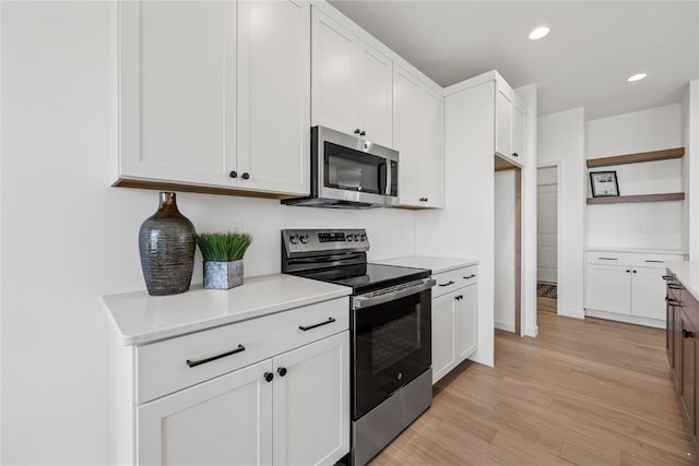 kitchen with light hardwood / wood-style floors, appliances with stainless steel finishes, and white cabinets