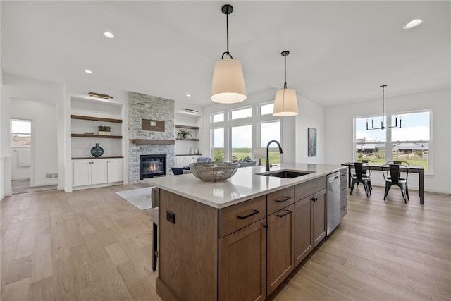 kitchen with built in shelves, plenty of natural light, light hardwood / wood-style floors, and a stone fireplace