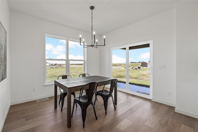 dining area featuring hardwood / wood-style flooring, a healthy amount of sunlight, and a chandelier