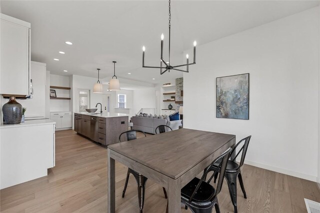 dining room with light hardwood / wood-style floors, sink, and an inviting chandelier