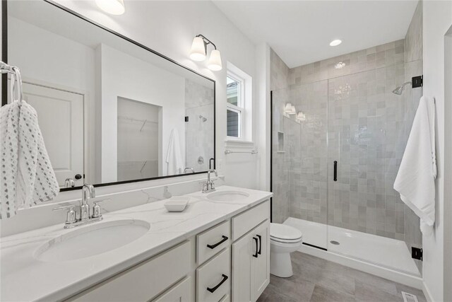 bathroom with tile patterned flooring, vanity, walk in shower, and toilet