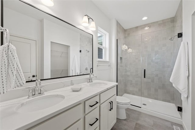 full bath featuring a stall shower, a spacious closet, and a sink