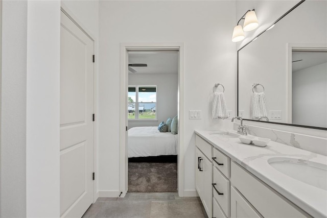 bathroom featuring a sink, double vanity, ensuite bath, and baseboards