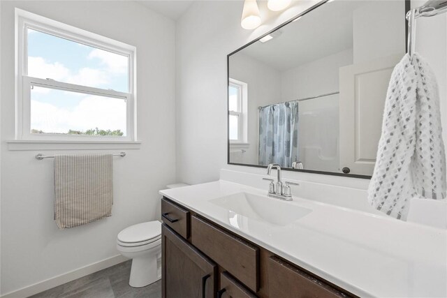 bathroom with a wealth of natural light, tile patterned flooring, vanity, and toilet