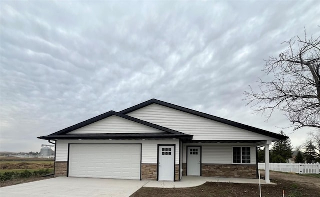 view of front of property featuring a garage, concrete driveway, and fence