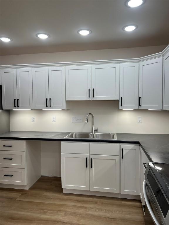 kitchen with recessed lighting, light wood-style floors, white cabinets, a sink, and range