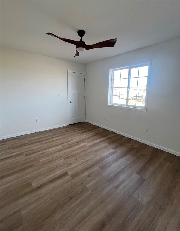 empty room featuring ceiling fan, baseboards, and dark wood finished floors