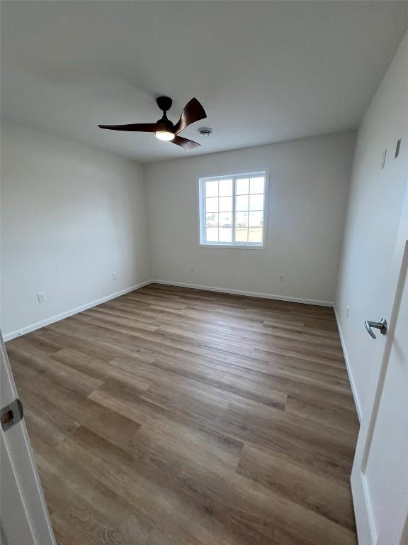 empty room featuring ceiling fan, wood finished floors, and baseboards