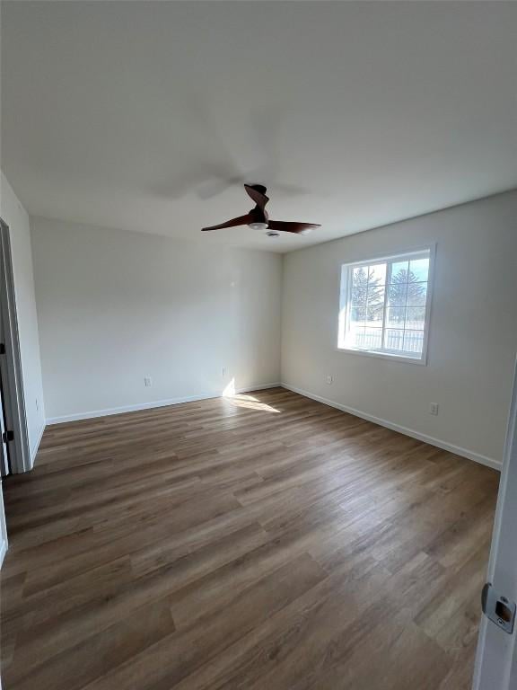 empty room featuring a ceiling fan, baseboards, and wood finished floors