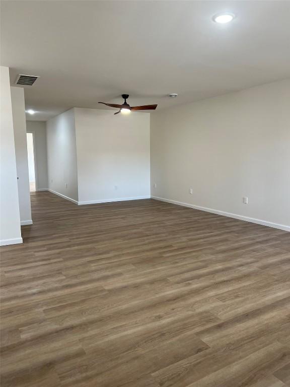 spare room featuring baseboards, ceiling fan, visible vents, and wood finished floors