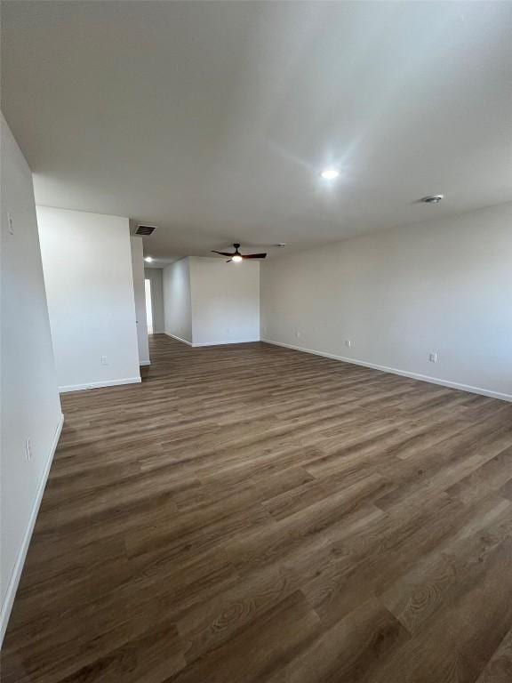 unfurnished room featuring dark wood-style floors, baseboards, visible vents, and a ceiling fan