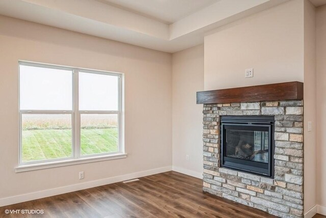 unfurnished living room with a fireplace, plenty of natural light, and dark hardwood / wood-style flooring