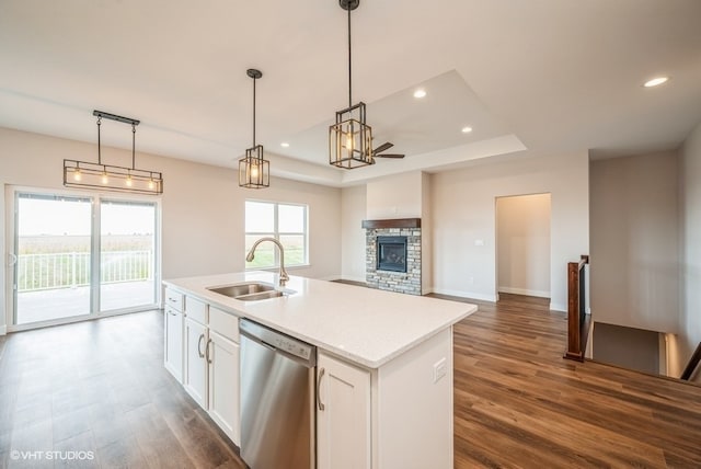 kitchen featuring dishwasher, a center island with sink, white cabinetry, and a fireplace