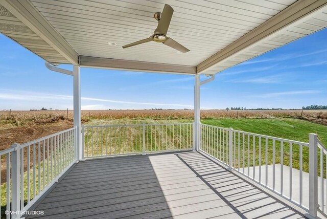 wooden deck featuring a lawn, ceiling fan, and a rural view