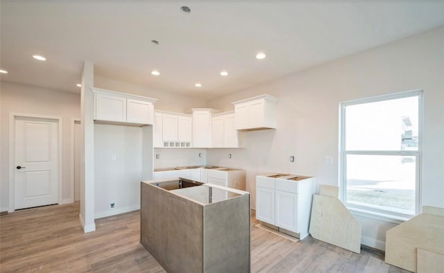 kitchen with light hardwood / wood-style flooring, a kitchen island, and white cabinets