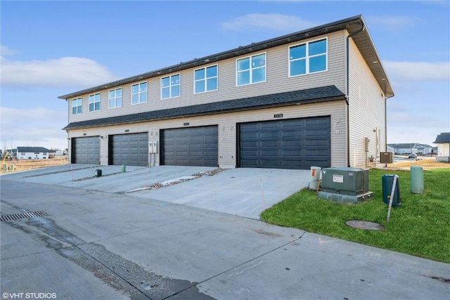 exterior space with a garage, a front yard, and central AC unit