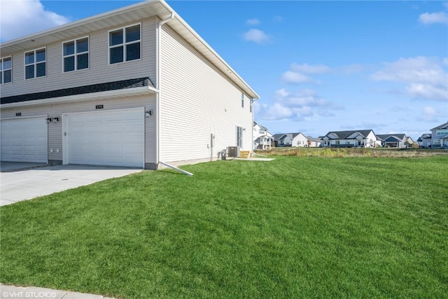 view of side of property featuring cooling unit, a garage, and a lawn