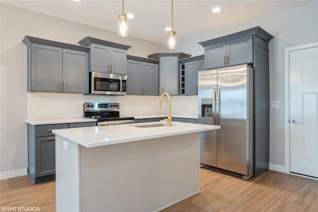 kitchen featuring pendant lighting, sink, an island with sink, and appliances with stainless steel finishes