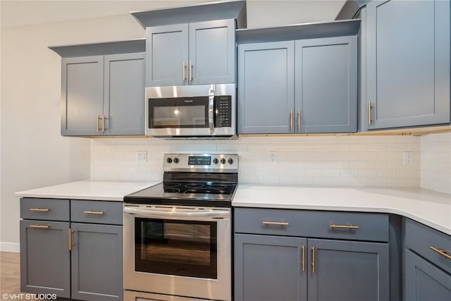 kitchen with appliances with stainless steel finishes, hardwood / wood-style floors, and decorative backsplash